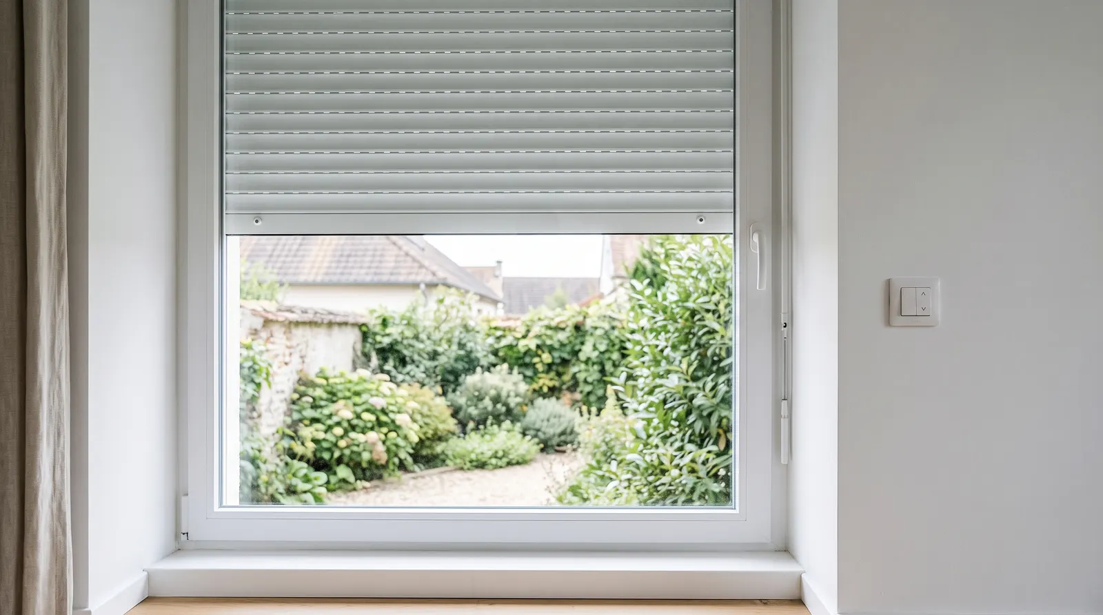 Fenêtre vue de l'intérieur, volet roulant droit descendu à mi-hauteur, interrupteur de volet au mur