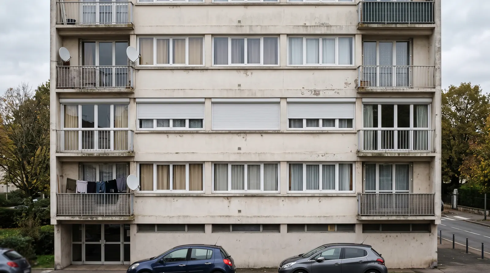 Façade d'immeuble avec des volets roulants électriques arrêtés à des hauteurs différentes
