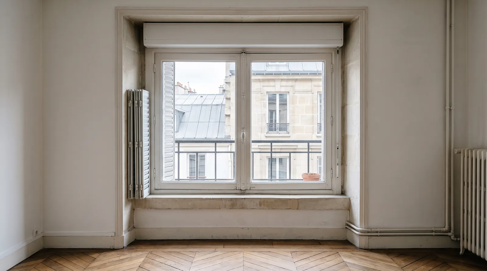 Grande fenêtre parisienne avec persiennes métalliques repliées et coffre de volet roulant posé sous le linteau